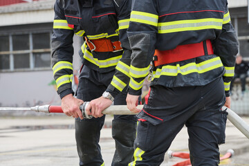 Fototapeta premium Firefighters Working Together Holding a Fire Hose During Emergency Training and Response Operation