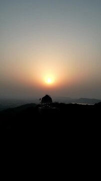 Stunning vertical aerial drone view of an ancient Hindu temple dome (chhatri) on a hilltop, bathed in the warm, golden light of the sunset over Bundi, Rajasthan &ndash; 2025