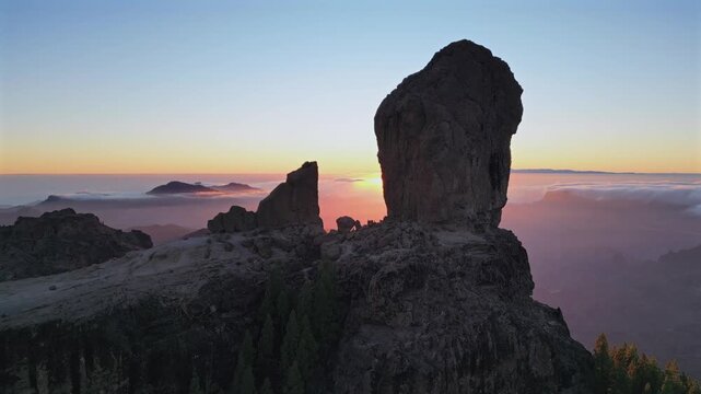 Breathtaking aerial footage of the iconic Roque Nublo volcanic rock in Gran Canaria. The sun setting over a sea of clouds creating a stunning landscape