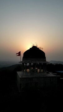 Stunning vertical aerial drone view of an ancient Hindu temple dome (chhatri) on a hilltop, bathed in the warm, golden light of the sunset over Bundi, Rajasthan &ndash; 2025