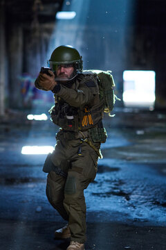 Tactical Soldier In Combat Gear Aiming Pistol Inside Abandoned Building Under Dramatic Light