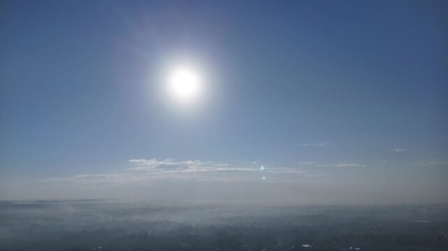 Aerial view of bright sun over morning hazy horizon and blue sky