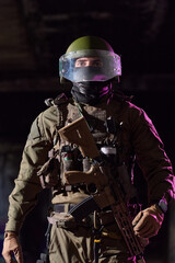 Naklejka premium Tactical Soldier in Riot Helmet and Tactical Gear Holding Assault Rifle in Low Light
