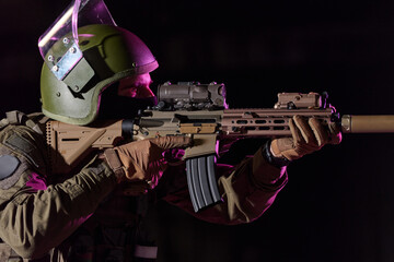 Obraz premium Soldier Aiming Tactical Rifle With Helmet, Night Optics And Suppressor In Low Light