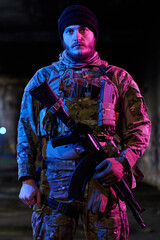 Fototapeta premium Armed Tactical Soldier In Camouflage Gear Holding Assault Rifle Under Neon Lighting