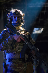 Fototapeta premium Armed Tactical Soldier in Camouflage Gear Holding Rifle in Low Light Urban Environment