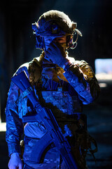 Fototapeta premium Armed Soldier in Tactical Gear and Helmet Holding Assault Rifle in Dramatic Low Light