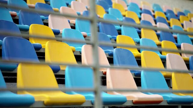 Neatly arranged rows of colorful seats inside a large arena awaiting visitors. The scene represents preparation for sporting events, live performances, festivals, and public entertainment.