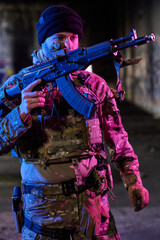 Fototapeta premium Armed Soldier In Tactical Gear Holding Rifle In Urban Night Operation With Colorful Lighting
