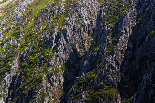 Detailed view of steep rocky cliff textures with green vegetation in Karkonosze National Park, Poland