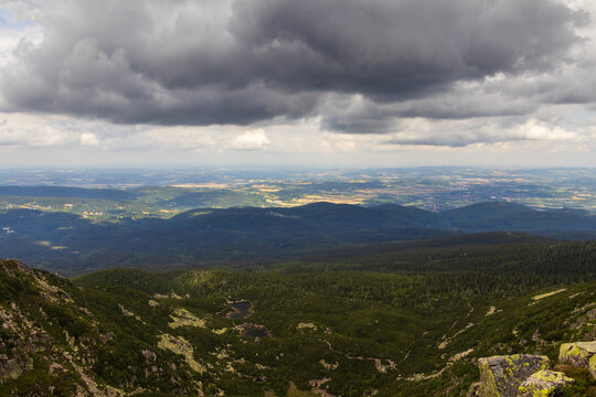 Scenic panoramic view of a mountain valley and distant plains under dramatic storm clouds in Karkonosze, Poland