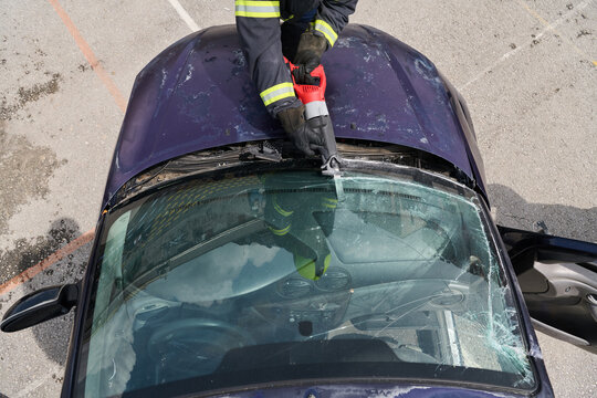 Firefighter Using Rescue Tool To Cut Windshield During Vehicle Extrication After Car Accident