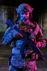 Fototapeta premium Armed Soldier In Tactical Gear With Assault Rifle Wearing Helmet And Camouflage In Urban Night Scene