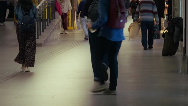 People legs walking blurred crowded train station floor movement motion. Low angle view of travelers legs walking with luggage backpacks bags. Blurred motion of diverse people walking on pedestrian co