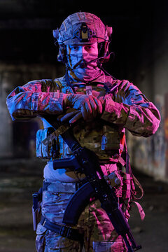 Armed Tactical Soldier in Camouflage Gear With Rifle and Helmet Under Dramatic Colored Lighting