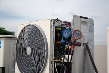 Air conditioner service .The air conditioner technician is using a gauge to measure the refrigerant...