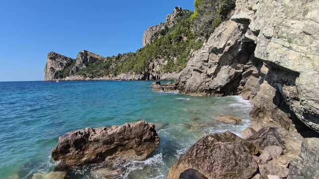 Rough sea waves crashing on rocky shore at Marina del Cantone, Nerano, Sorrento Peninsula, Italy. Historic watchtower on the cliff, turquoise water and sunny summer landscape video footage