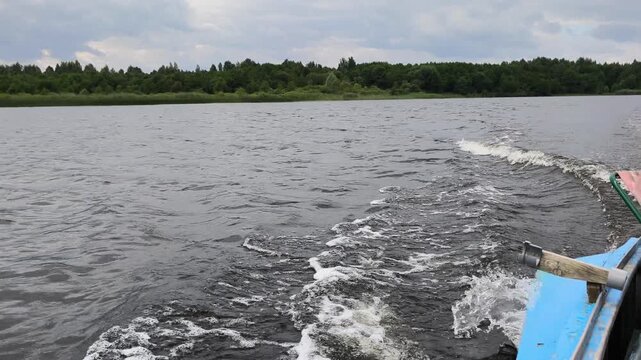 A sleek boat pulls away from the shore, carving a frothy wake across the calm water as the horizon stretches into the distance under a soft, cloudy sky timeless moment of departure and adventure.