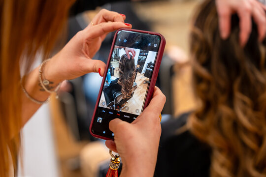 Hairdresser styling client hair then capturing it with smartphone