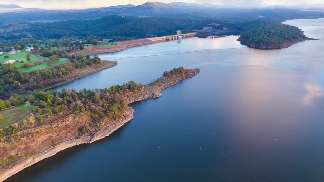 Aerial video flying over Lake Keepit Dam and the surrounding landscape in NSW, Australia. The expansive reservoir, dam wall and rolling countryside