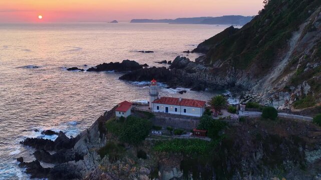Cudillero lighthouse in Asturias at sunrise, drone orbiting shot, famous tourist destination on the Atlantic coast of Spain, tourism in fishing village of Cudillero, travel in the north of Spain