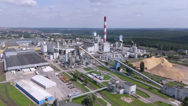 Aerial view of modern pulp and paper mill plant with industrial machinery and wood chips for manufacturing and supply chain