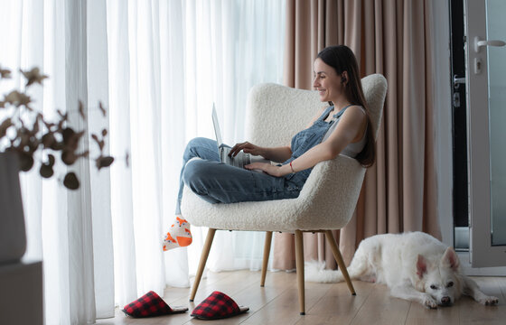 Woman working comfortably from home with laptop and dog