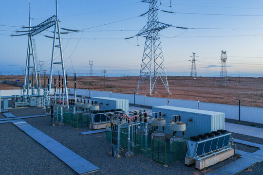High-voltage power transmission towers and electrical substation at sunset