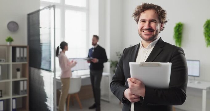 Businessman manager executive in office portrait smiling. He holds a clipboard with documents, showing leadership, recruiter focus and corporate success. Concept of firm management and hiring.