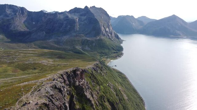 Aerial shot of mountain summit with steep drop-off to the ocean in Kvaloya Norway