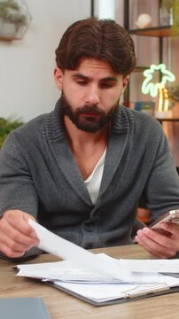 Indian man at home audits bills with smartphone runs finger on rows finds wrong card charge and flags issue. Arabian guy at desk checks payments cancels order shows anger plans dispute bank support.