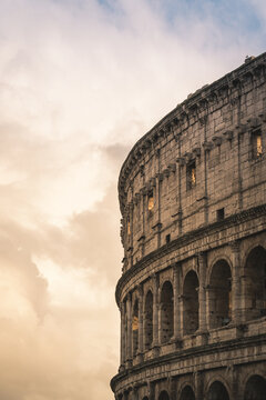 Colosseum, an iconic Roman amphitheater and UNESCO World Heritage Site, stands against a warm, cloudy evening sky, illustrating historic architecture and cultural heritage in Rome
