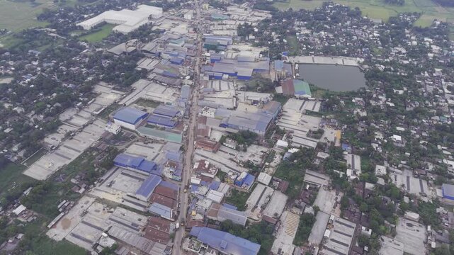 Drone shot moving downward from a higher altitude over an industrial and residential area in Khajanagar, Kushtia, with factories, buildings, infrastructure, and rural surroundings.