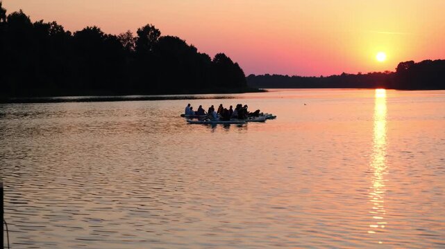 Moscow. Russia. 23.07.2026 People paddling on stand up paddle boards on lake at sunset. Group of man and woman enjoying outdoor water sport activity during golden hour at summer evening.