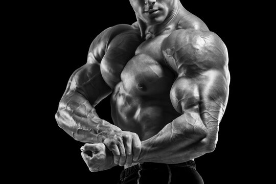 Muscular man showing muscles, isolated on black background. Bodybuilder male naked torso abs