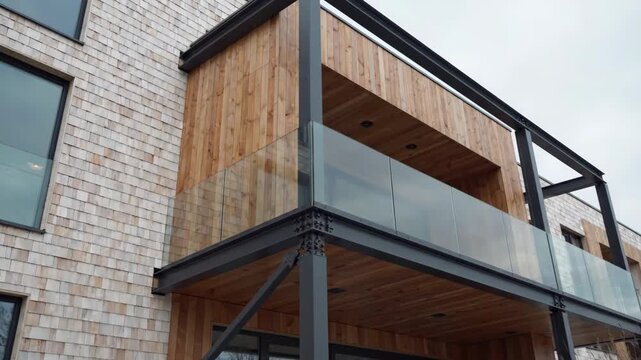 Modern Apartment Building Facade with Wooden Balcony and Glass Railings.