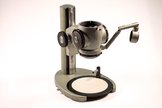Stereo microscope stand with adjustable optical head and accessory holder isolated on a white background. Precision laboratory instrument for microscopy and specimen observation.