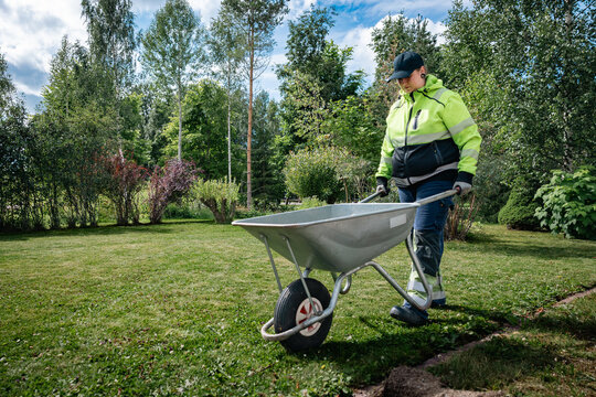 woman is pushing wheelbarrow in the garden