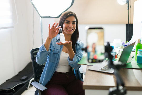 Young smiling woman recording video blog at home studio, promoting beauty products for social media followers