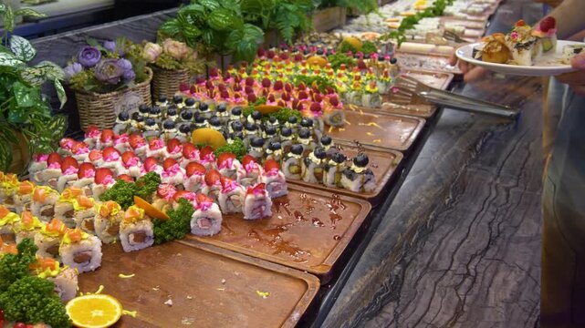 Person choosing fresh sushi at luxury buffet restaurant