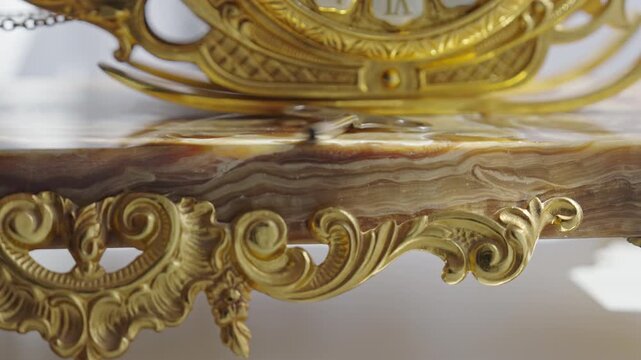Ornate vintage pendulum clock with gold details and marble base swinging