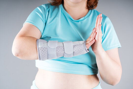 Unrecognizable woman wearing wrist orthopedic brace for carpal tunnel syndrome, sprain and joint pain rehabilitation. Gray medical splint