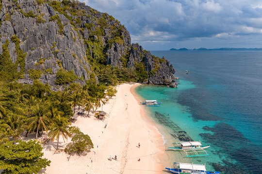 Aerial view of Black island in the Philippines with beautiful sand beach, stranded shipwreck and moared boats. 