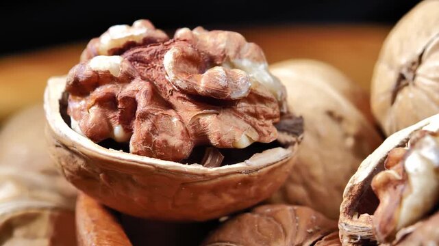 Fresh organic walnuts in a rustic wooden bowl on a wooden table. Healthy natural nuts rich in nutrients, suitable for healthy eating, snacks, and food backgrounds.