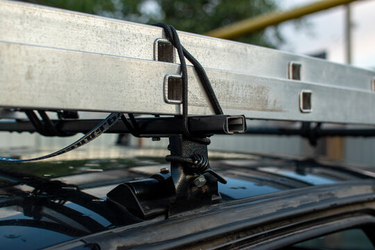 Extension ladder strapped to a car roof rack