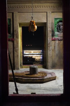 Ancient Shiva lingam inside riverside temple with illuminated boat beyond