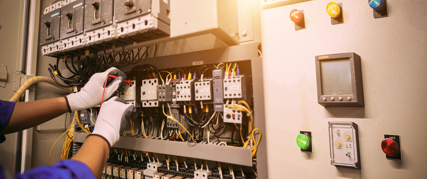 Electrical service technician use electricity measuring tools equipment checking electric current circuit breaker terminal panel and cable wiring main power distribution board for maintenance system.
