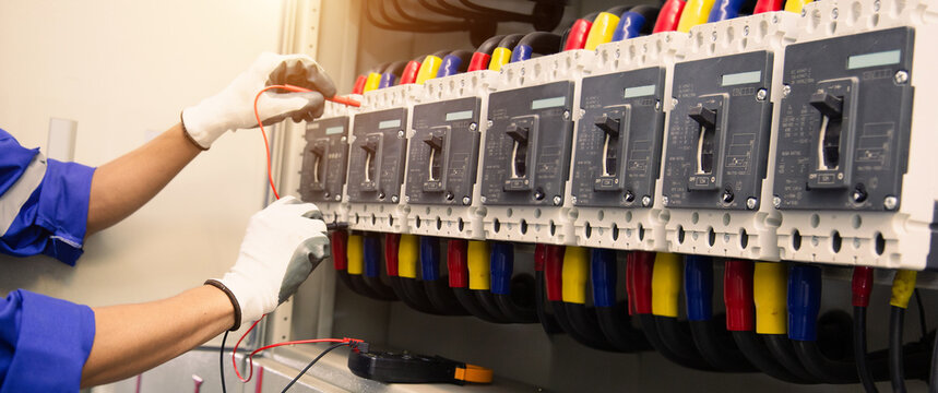 Electrical service technician use electricity measuring tools equipment checking electric current circuit breaker terminal panel and cable wiring main power distribution board for maintenance system.