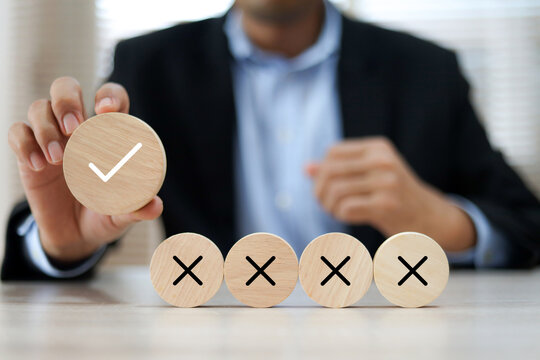 Hand choose check mark with cross symbol on wooden toy stack for true or false changing mindset or way of adapting to change leader and transform quiz answer and poll concept.