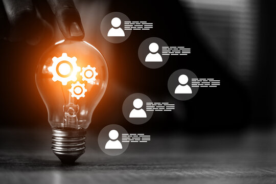 Businessman's hand with HR human resources icons on light bulb for leader or group teamwork people officer or business planning or team player and personnel management job performance.